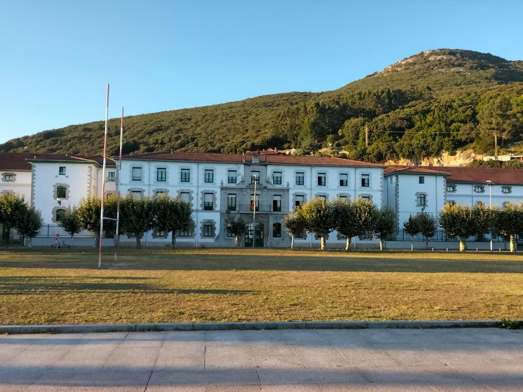 a large white building with a hill in the background at Apartamento Virgen del Carmen in Santoña