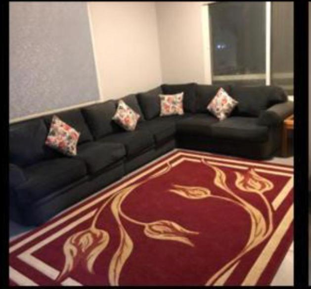 a living room with a black couch and a red carpet at شقة للايجار بالسنة in Jeddah