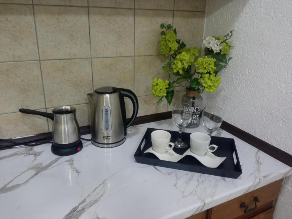 a counter with two cups and glasses on a tray at Green Apartment in Strumica