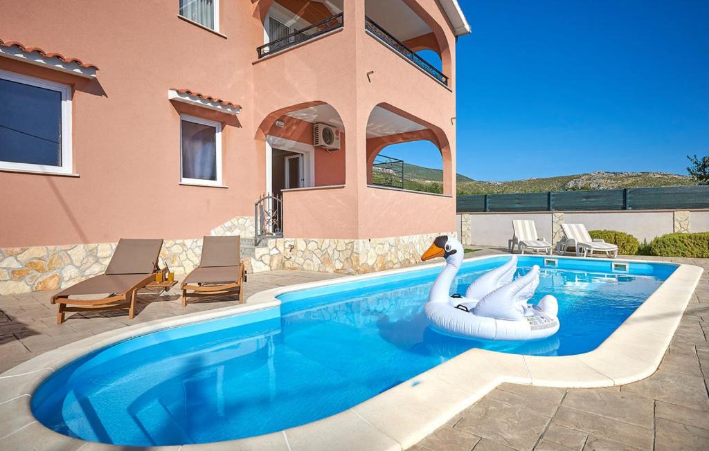 una piscina con un flotador de cisnes frente a una casa en Villa Kate, en Trogir