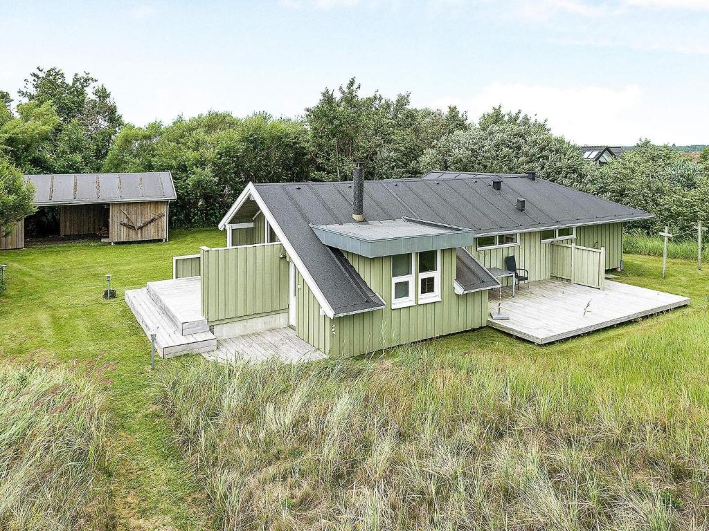 een groen huis met een terras in een veld bij 6 person holiday home in Jerup in Jerup