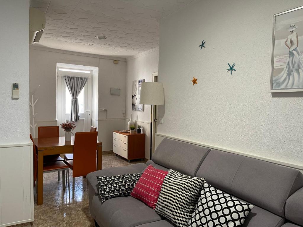een woonkamer met een grijze bank met kussens bij Lleida 25, casa de poble a planta baixa amb àmplia terrassa equipada in Sant Carles de la Ràpita