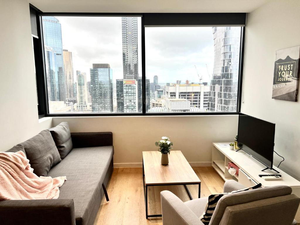 ein Wohnzimmer mit einem Sofa und einem großen Fenster in der Unterkunft Readyset Apartments at Manhattan in Melbourne