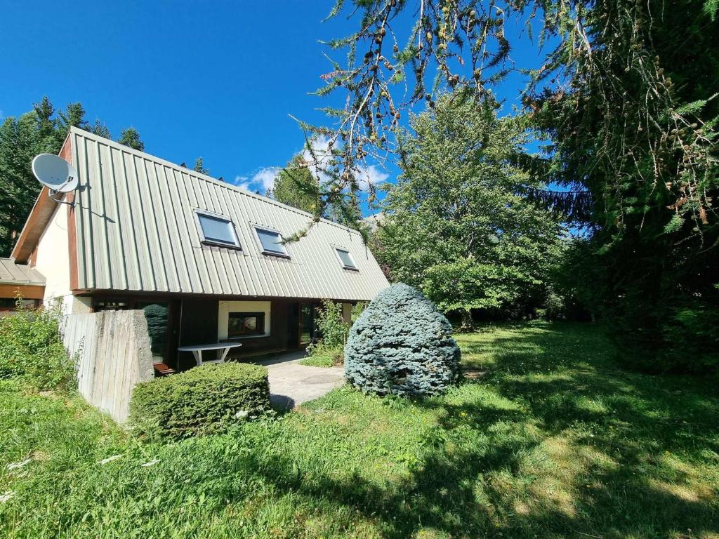 una casa con techo y algunos arbustos y árboles en Chalet spacieux 10 pers, 4 chambres, jardin, cheminée, animaux OK, ménage fin séjour option - FR-1-393-38, en Saint-Michel-de-Chaillol
