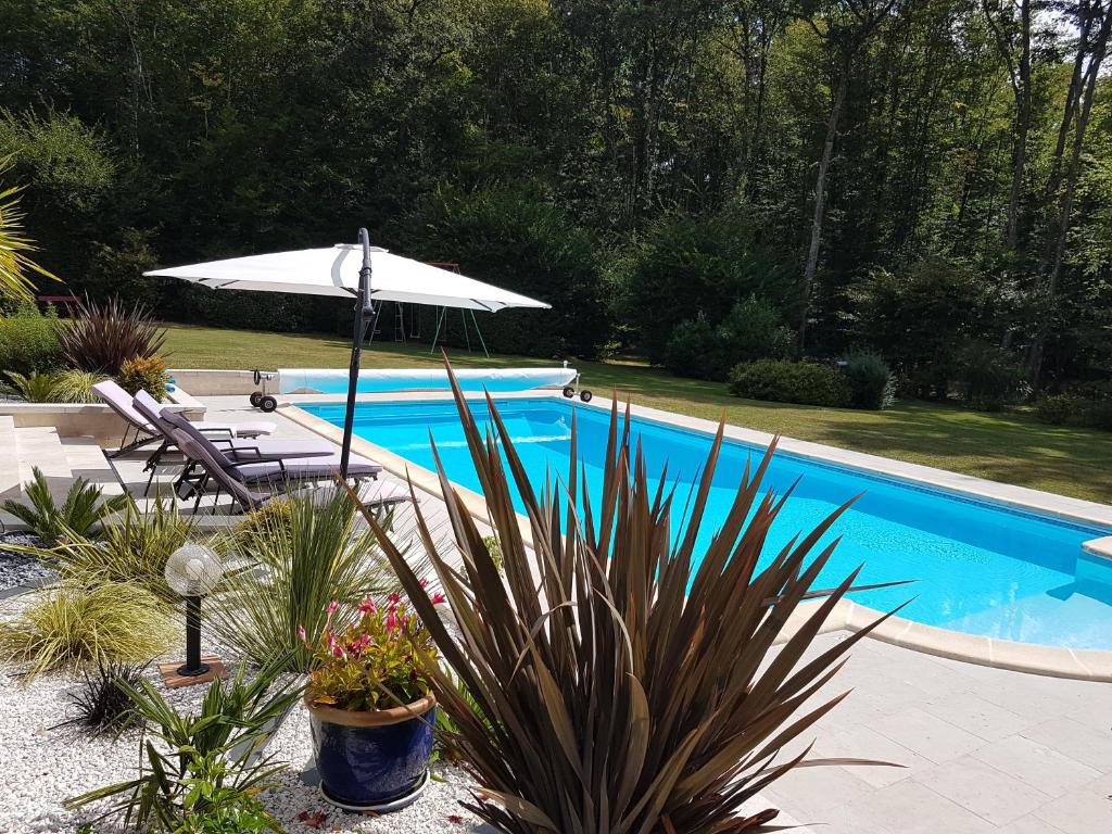 een zwembad met een parasol en een stoel en een tafel en sidx sidx bij Logement aux portes de chambord in Mont-près-Chambord