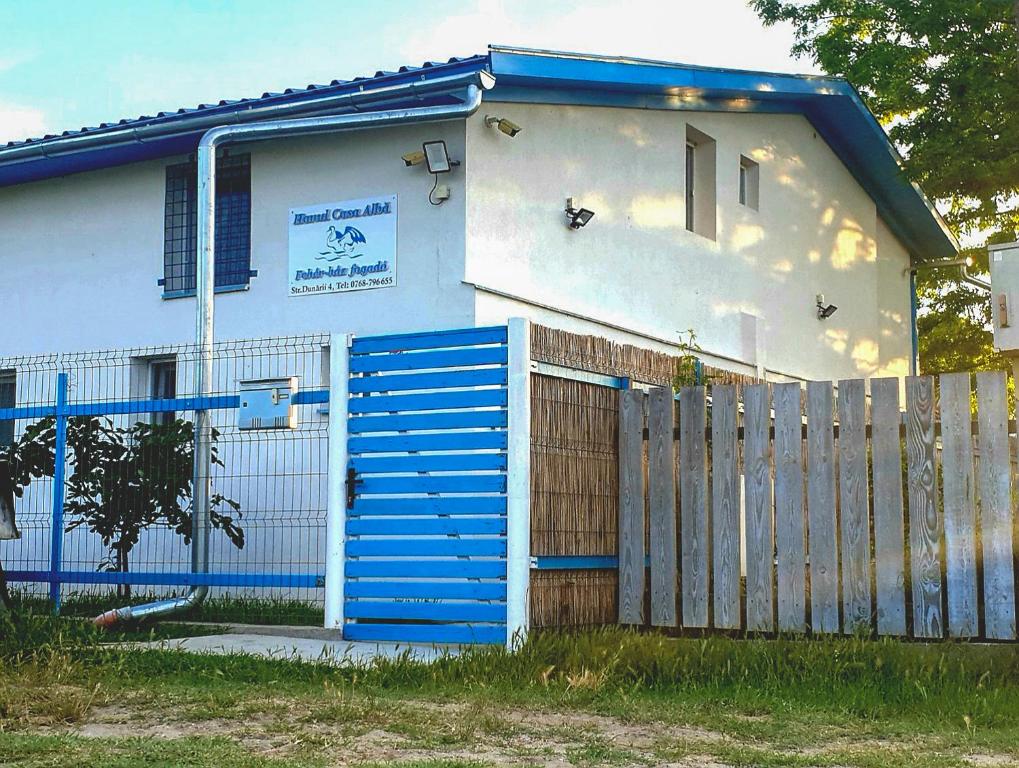 een huis met een blauwe poort en een hek bij Hanul Casa Alba Fehér Ház Fogadó in Periprava