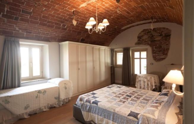 een slaapkamer met een bed en een bakstenen muur bij La locanda del cuore in Carrù