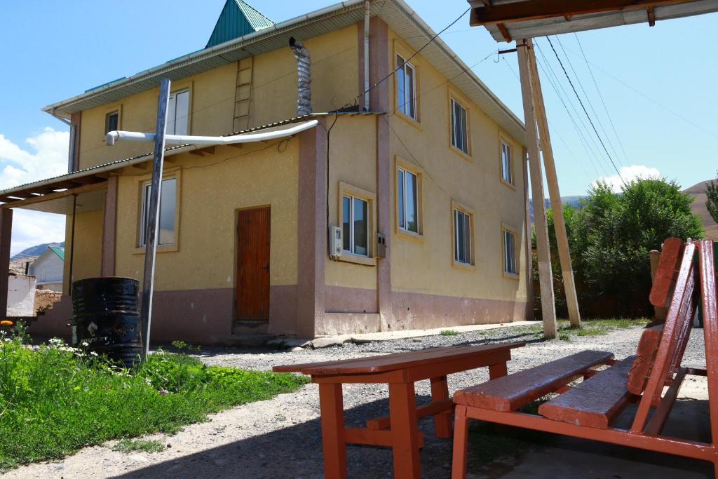 ein Haus mit einer Bank davor in der Unterkunft Almaz Guesthouse Naryn in Orto-Saz
