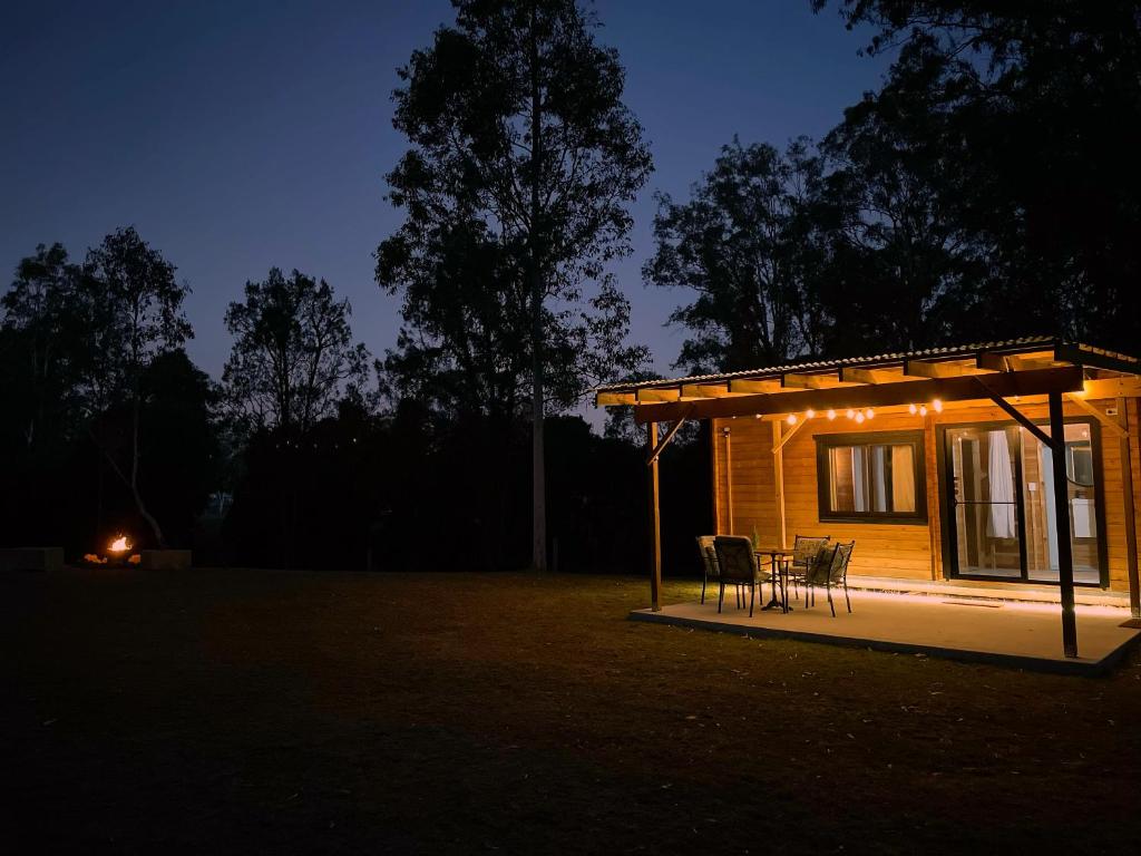 a small cabin with a table and chairs at night at Country Creek Cabin in Bromfleet