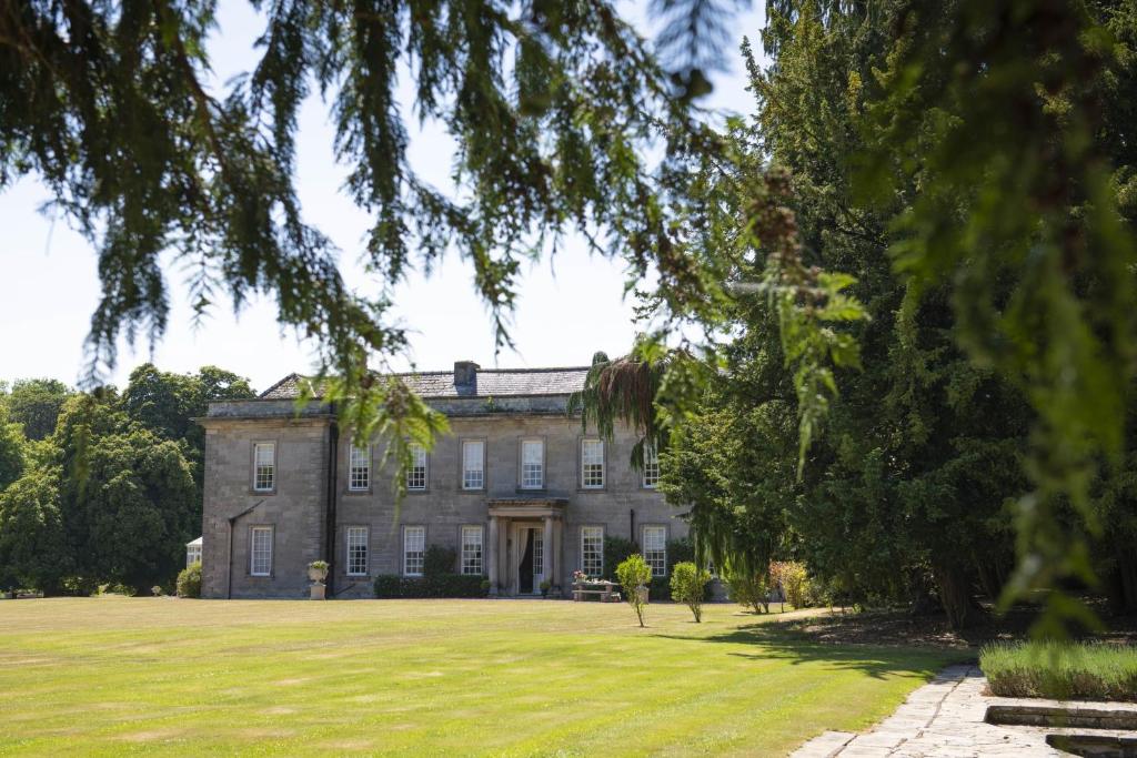 una casa antigua con un gran patio de césped en Eslington East Wing en Alnwick