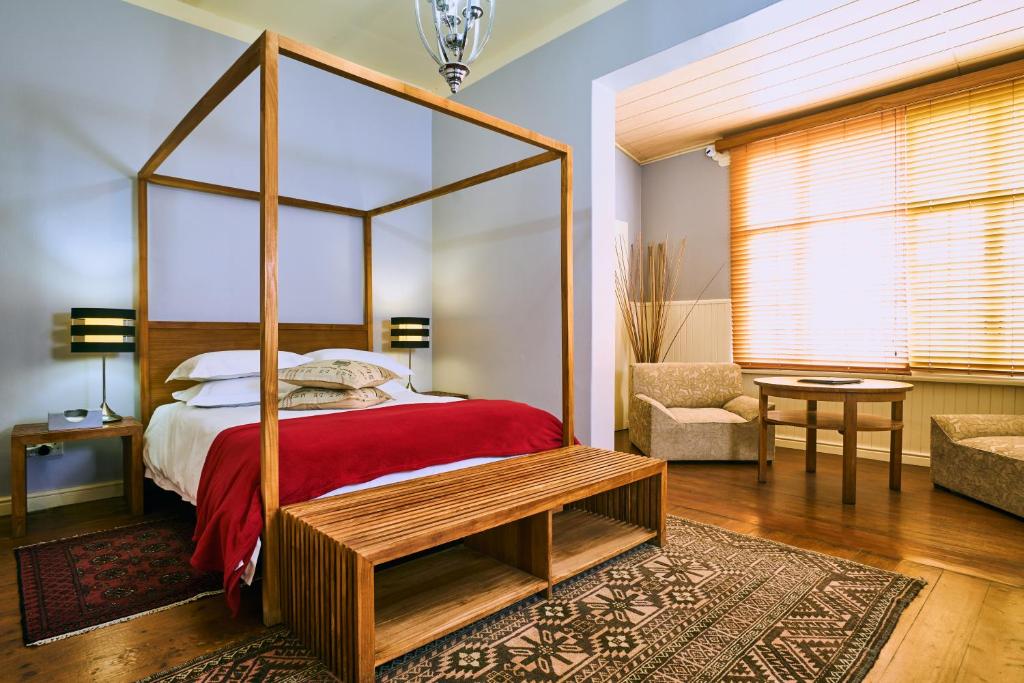 a bedroom with a four poster bed with a red blanket at Villa Margherita in Swakopmund
