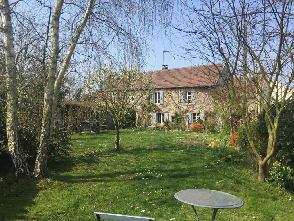 una casa con un tavolo di fronte a un cortile di Grande maison avec jardin arboré a Survilliers