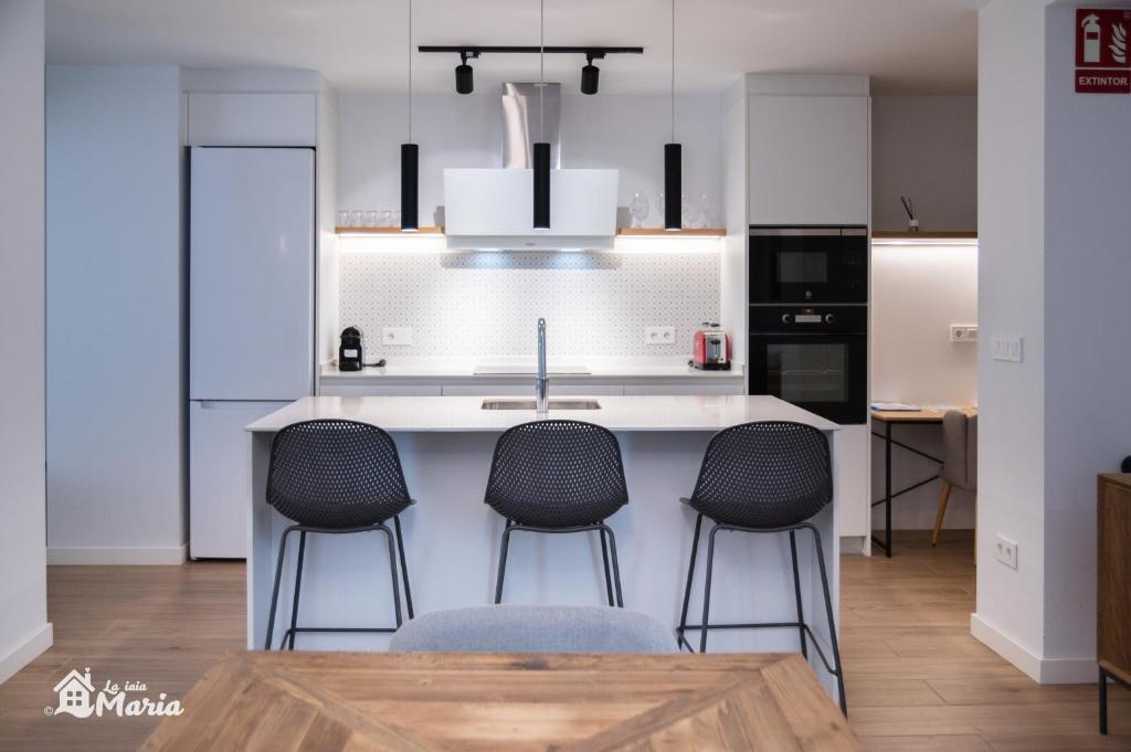 a kitchen with a sink and four bar stools at La Iaia Maria in Gandía