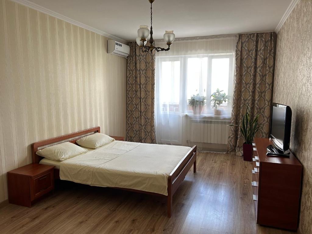 een slaapkamer met een bed, een televisie en een raam bij Apartments Kharkivs'ke highway in Kiev