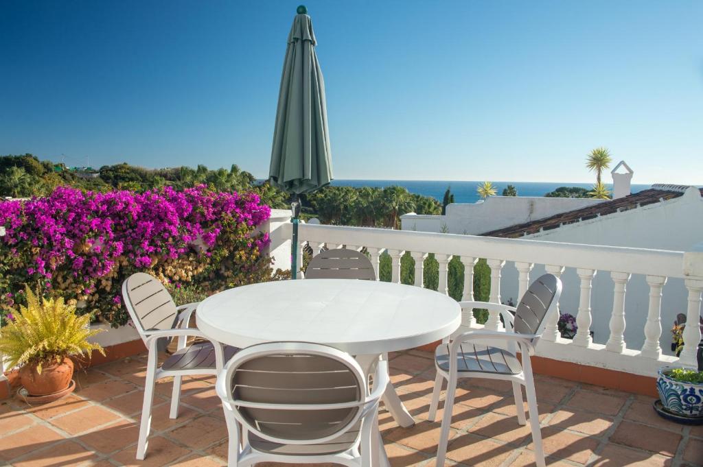 une table et des chaises blanches sur un balcon avec des fleurs violettes dans l'établissement Tetuan 7 Oasis Properties, à Nerja