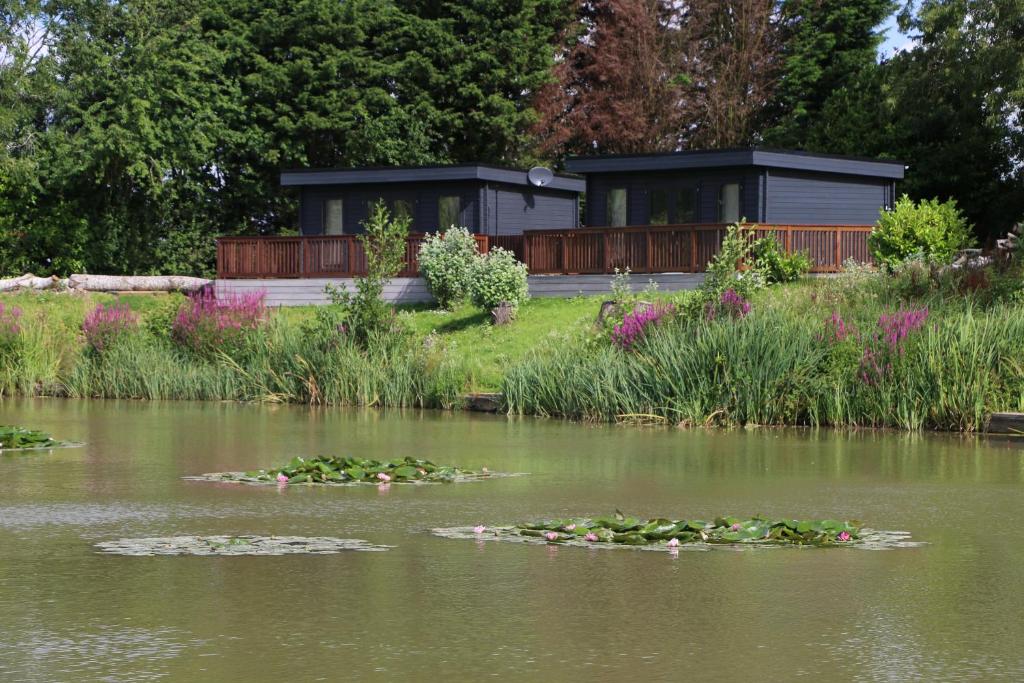 a lake with lilly pads in the water with a building at Lakeside Lodges in Leicester