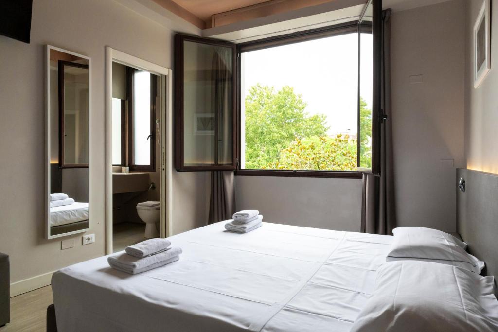 a bedroom with a large white bed and a window at Plus Florence in Florence