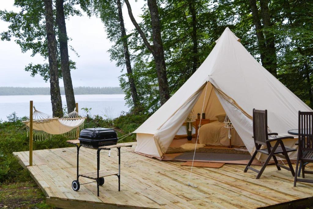 a white tent with a hammock and a grill at Glamping Bolmen, Seaview, free canoe in Odensjö