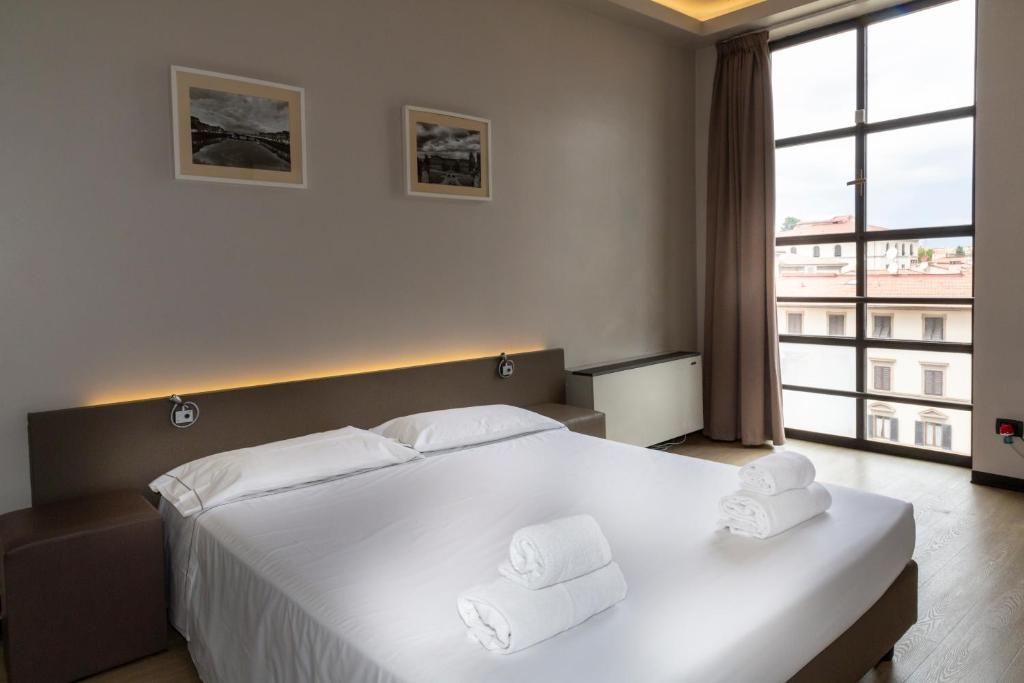 a bedroom with a large white bed with two white towels at Plus Florence in Florence