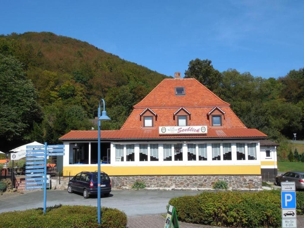 a building with a red roof in a parking lot at Ferienwohnung-Seeblick-Edersee in Waldeck