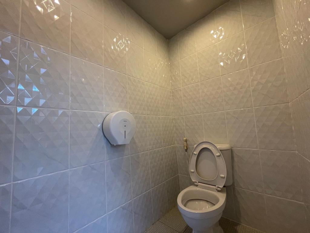 a bathroom with a toilet with a soap dispenser on the wall at Comfort Zone Hostel @ Tha Pae in Chiang Mai
