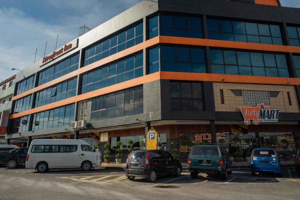 un gran edificio con coches estacionados en un estacionamiento en Capital O 90083 Riverfront Inn en Bintulu