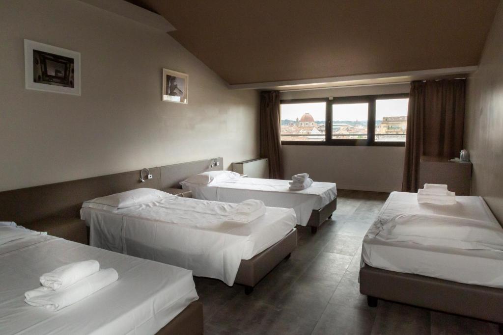 a hospital room with three beds and a window at Plus Florence in Florence
