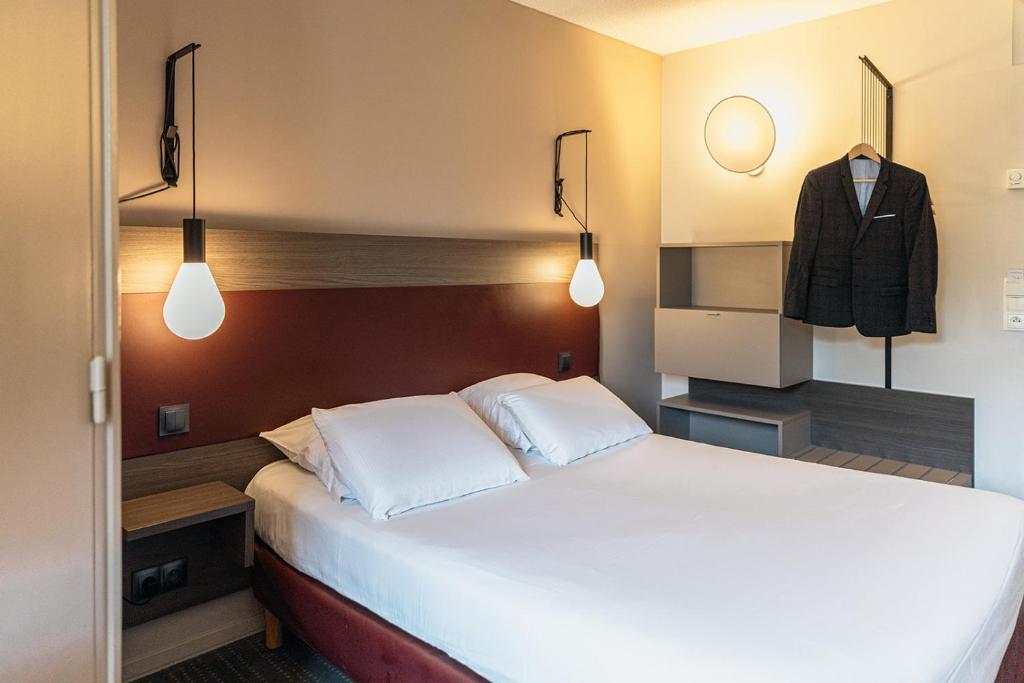 een slaapkamer met een bed en een jas aan de muur bij Kyriad Metz Centre - Restaurant Moze in Metz