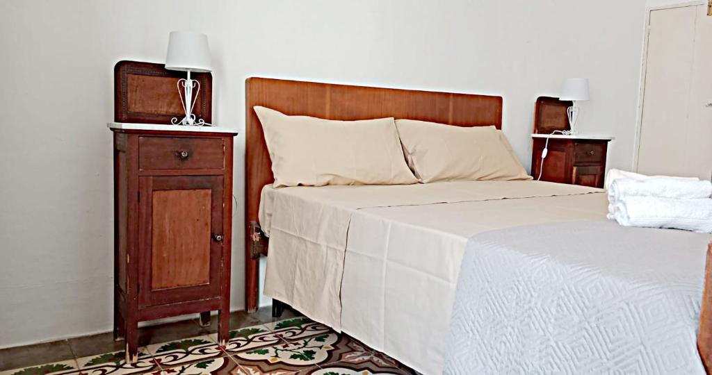 een slaapkamer met een bed en een houten hoofdeinde en een nachtkastje bij COLOMBO casa per vacanze in corte salentina in Matino