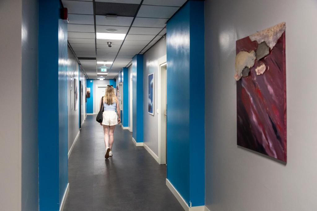 a woman walking down a corridor in a hallway with blue walls at Plus Florence in Florence