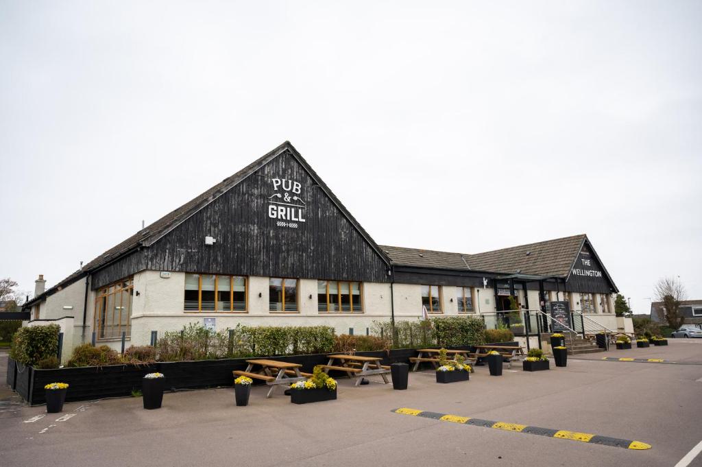 een zwart-wit gebouw met picknicktafels op een parkeerplaats bij Wellington Hotel by Greene King Inns in Aberdeen