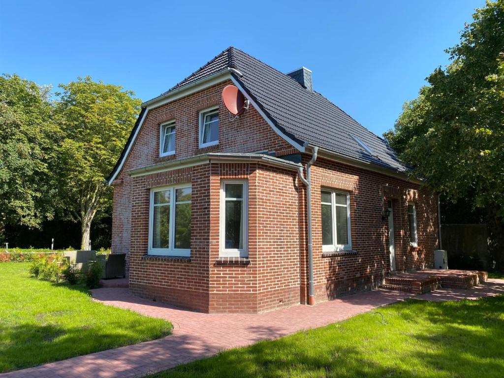 een rood bakstenen huis met een zwart dak bij Villa Pewsum in Krummhörn