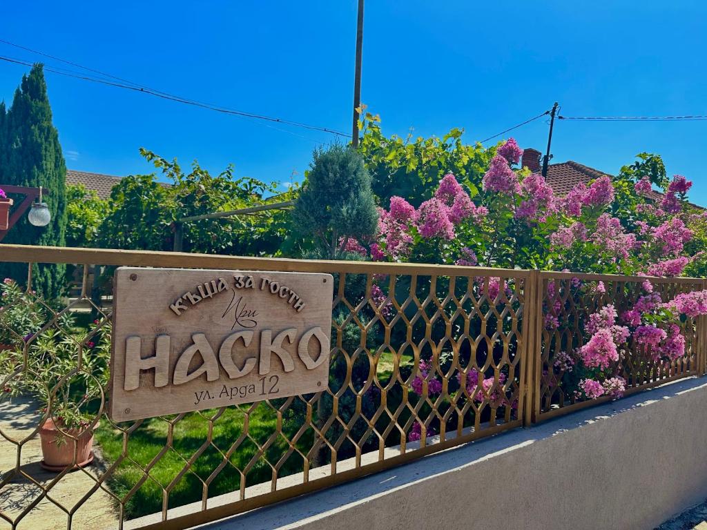 a sign on a fence with flowers behind it at При Наско in Shabla