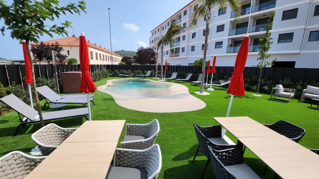 a patio with tables and chairs and a swimming pool at Sercotel Plana Suites in Vall de Uixó