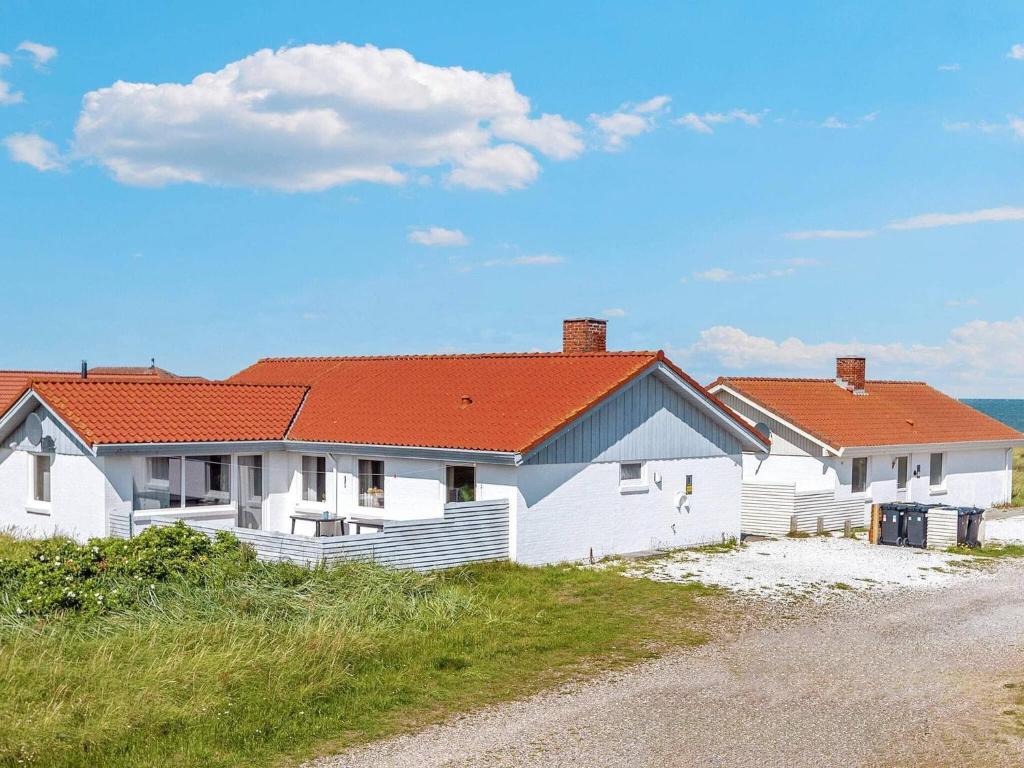 ein weißes Haus mit orangefarbenem Dach am Strand in der Unterkunft Holiday Home Sandnæshagevej II in Lild Strand