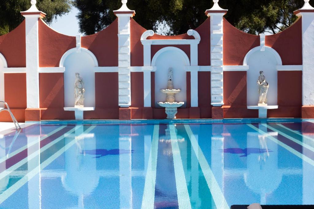 une piscine avec une fontaine en face d'un bâtiment dans l'établissement Hotel Hacienda Montenmedio, à Vejer de la Frontera