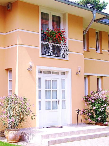 a house with two windows and a door with flowers at Horváth Apartman in Balatonlelle