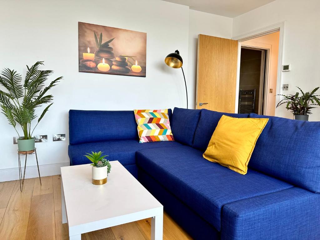 a blue couch in a living room with a table at Cosy Apartment Haywards Heath in Haywards Heath