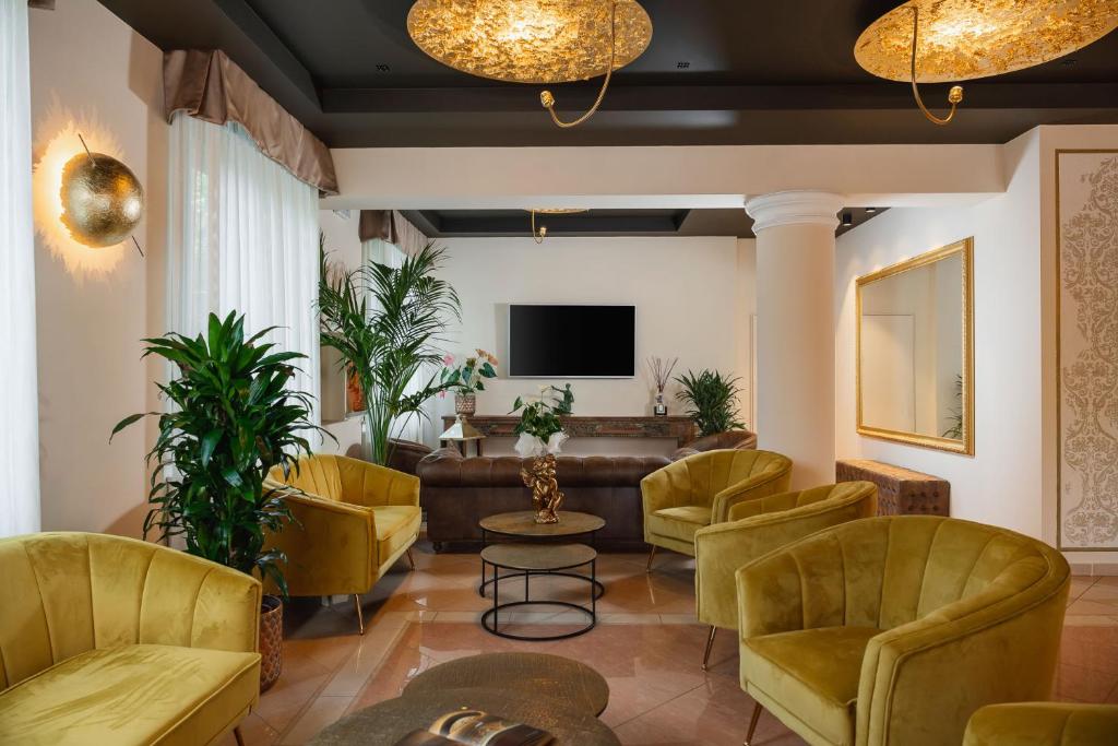 a lobby with yellow chairs and a couch and a tv at Hotel Mazzanti in Milano Marittima