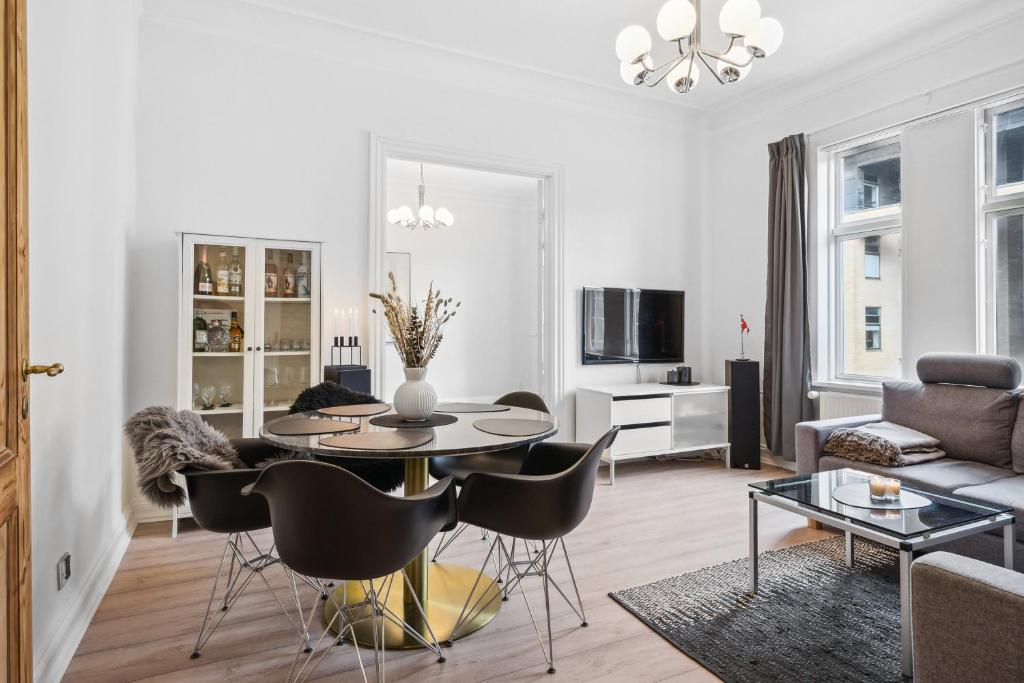 a white living room with a table and chairs at Lejlighed i hjertet af Aalborg in Aalborg