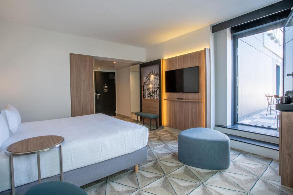 a hotel room with a bed and a tv at Courtyard by Marriott Paris Porte de Versailles in Issy-les-Moulineaux