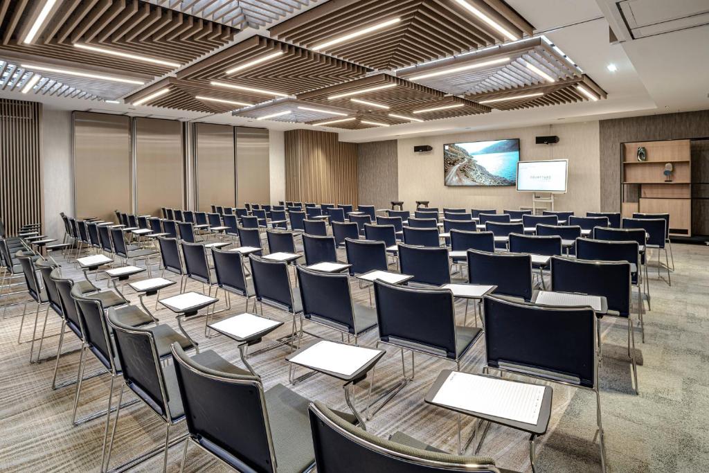 a room with rows of chairs and a screen at Courtyard by Marriott Paris Porte de Versailles in Issy-les-Moulineaux