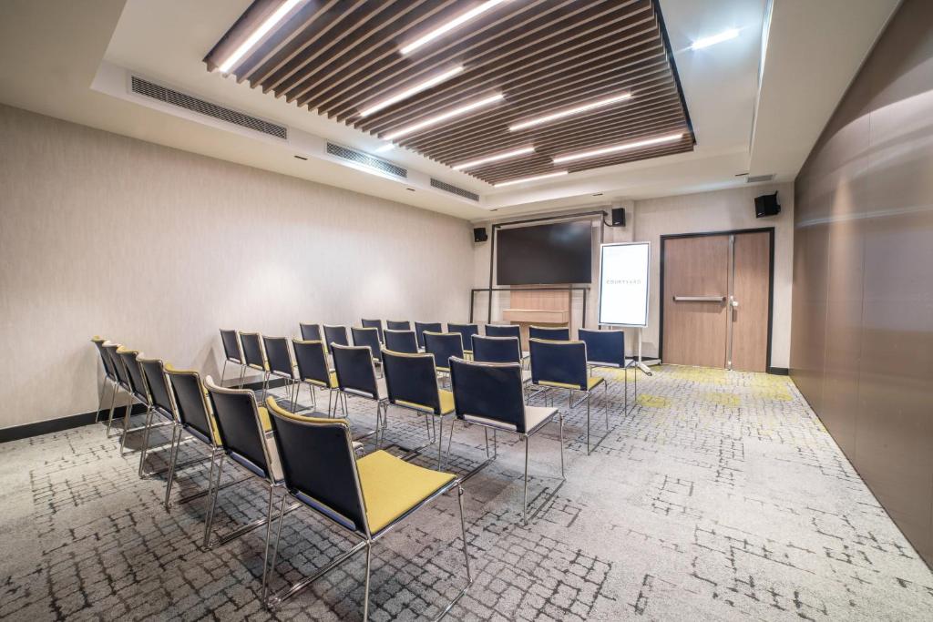 a conference room with chairs and a podium and a screen at Courtyard by Marriott Paris Porte de Versailles in Issy-les-Moulineaux