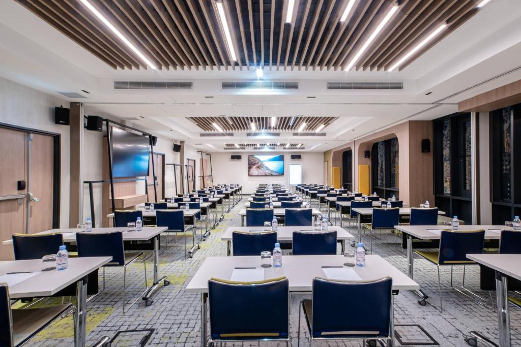 a conference room with tables and chairs and a projection screen at Courtyard by Marriott Paris Porte de Versailles in Issy-les-Moulineaux