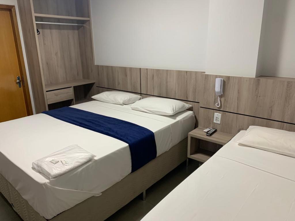 a bedroom with two beds and a phone on the wall at Hotel Seven in Goiânia