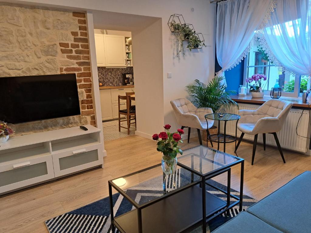- un salon avec une télévision et une table fleurie dans l'établissement Apartament Deluxe-Gontalowy, à Kazimierz Dolny
