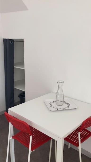 a white table with two red chairs and a vase on it at Studio au centre de Quimper RDC in Quimper