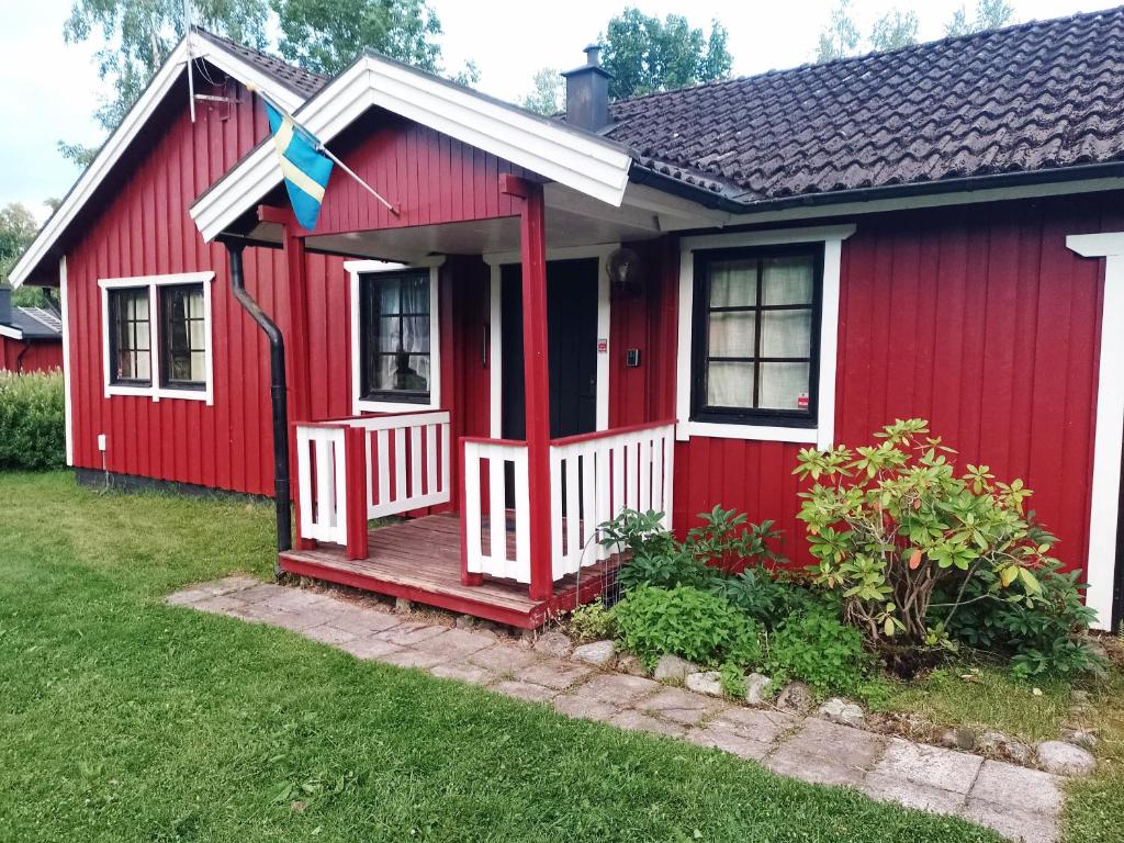 uma casa vermelha com um alpendre branco em Holiday house in Grythem, Orebro, within walking distance to lake em Örebro