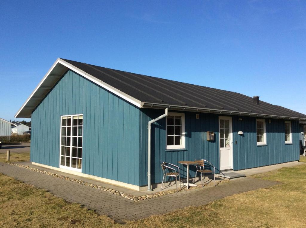 un edificio azul con una mesa y sillas delante de él en Lønne Feriepark Holiday House 53, en Lønne Hede