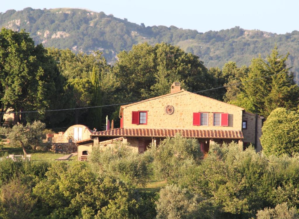 an old house in a field with mountains in the background at Case Bosco in Roccalbegna